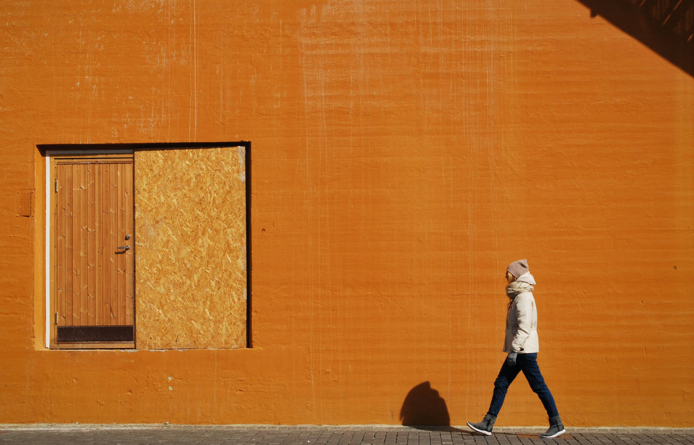 woman walking past an urban yellow wall